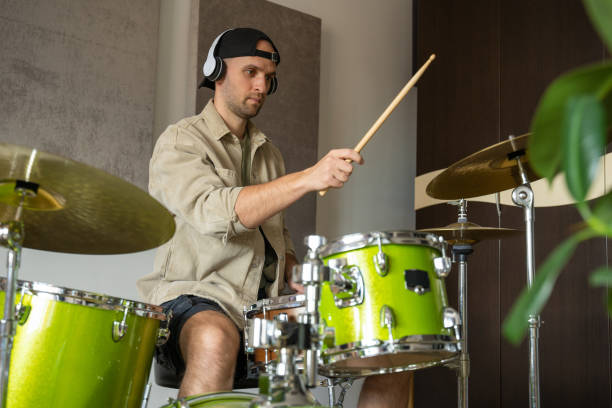istock Man professionally plays drums in equipped music studio 1409423486