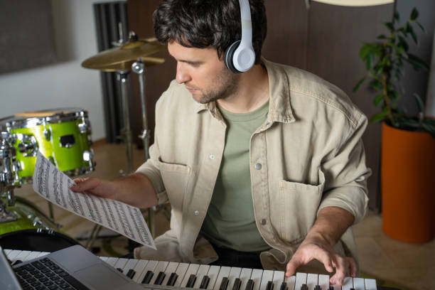 istock Man gives piano lesson via laptop playing notes from sheet 1409423501