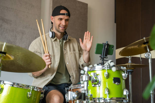 istock Man records drum lesson on phone and shows playing technique 1409423504