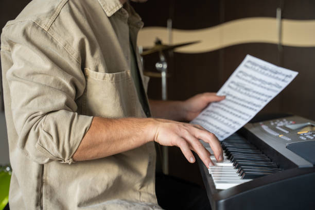 istock Young man checks music sheet and plays notes on synthesizer 1409423505