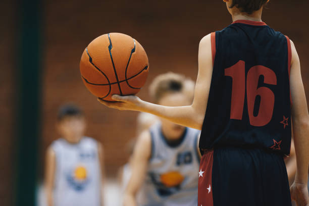 giovane giocatore di basket con palla classica. giocatore di basket di livello junior che tiene la palla da gioco. allenamento di pallacanestro per bambini - basketball child dribbling basketball player foto e immagini stock