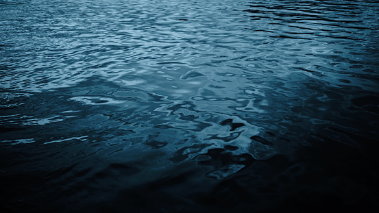 Fondo de agua azul negro. Reflejo de la luz. Olas. Ondas. Noche. Fondo oscuro dramático de la superficie del mar con espacio para el diseño. photo
