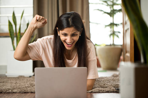 istock Woman celebrating success using laptop at home 1409424356