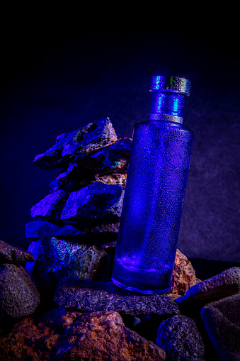 Blue glass bottle on the background of rocks in the river