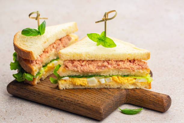 Two Tuna sandwich with boiled egg, mayonnaise, lettuce on a wooden board. stock photo