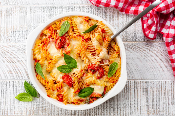 pasta alla sorrentina.  spiral shape fusilli pasta oven baked in casserole with tomato sauce, basil and mozzarella, parmigiano  cheese. italian meal, campania region. - mozzarella cheese italy tomato imagens e fotografias de stock