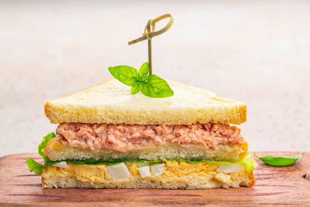 Close-up of Tuna sandwich with boiled egg, mayonnaise, lettuce on a wooden board. stock photo