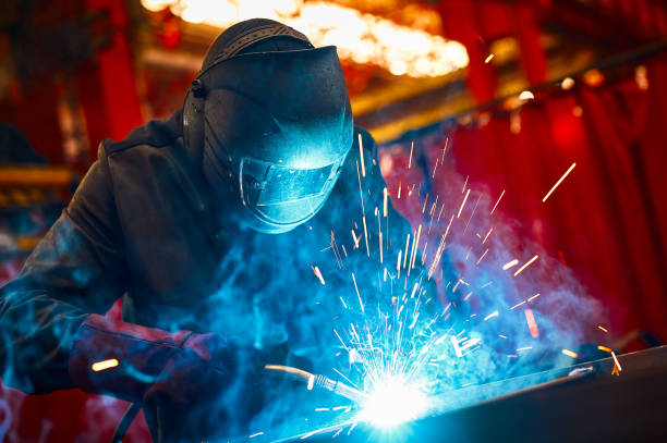 Laborer in protective mask welds manually metal frame stock photo