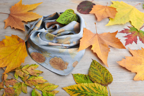 istock Hand-dyed silk scarf surrounded by autumn leaves. Eco-print technique 1409428569