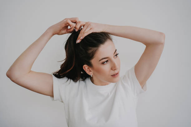 Brunette young woman making ponytail, dressed in white t-shirt. Beautiful student preparing at home gathering hair for comfortable learning at university. Girl looking aside close up. Brunette young woman making ponytail, dressed in white t-shirt. Beautiful student preparing at home gathering hair for comfortable learning at university. Girl looking aside close up. ponytail stock pictures, royalty-free photos & images