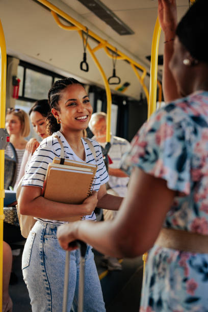 istock Student with books in arms talking to passenger on bus 1409431387