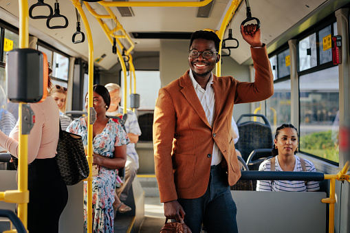 Elegante hombre de negocios afroamericano sonriendo en el autobús photo
