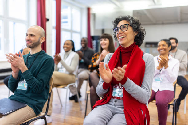 istock Multi-ethnic group of people sitting in audience clapping hands 1409432886