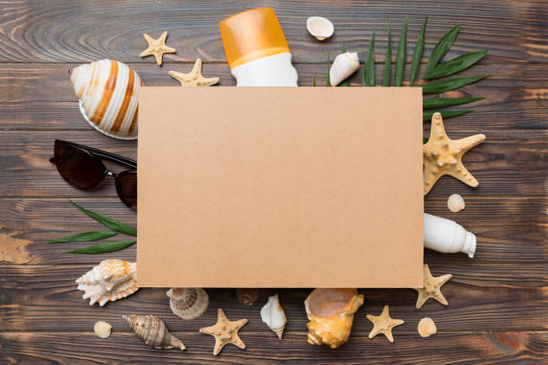 istock Summer time concept with blank greeting card and blank craft paper on colored background. Seashells from ocean shore in the shape of frame separated with space for text top view 1409433586