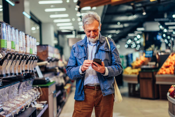 istock Senior man using phone while shopping in grocery 1409433719
