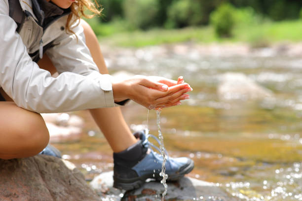 Trekker with cupped hands catching water from river