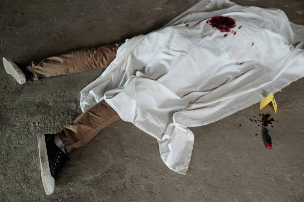 Above shot of dead body of young man in beige pants and black gumshoes Above shot of dead body of young man in beige pants and black gumshoes lying on asphalt in parking area after murder dead person stock pictures, royalty-free photos & images