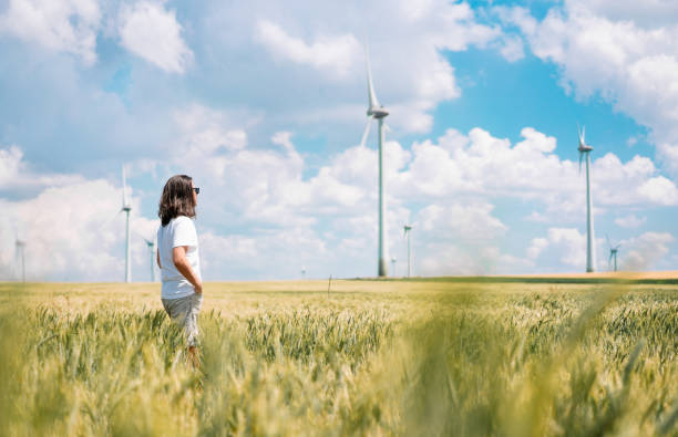 風力タービン農場のそばの麦畑に立つ男 - windmill cultivated land crop day ストックフォトと画像