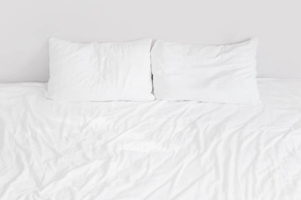 istock White bed with white linens with two pillows close up 1409437175