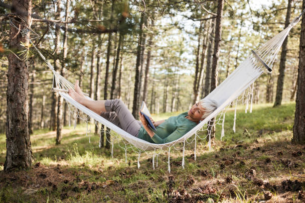 istock Happy senior woman reading a book in hammock. 1409437631