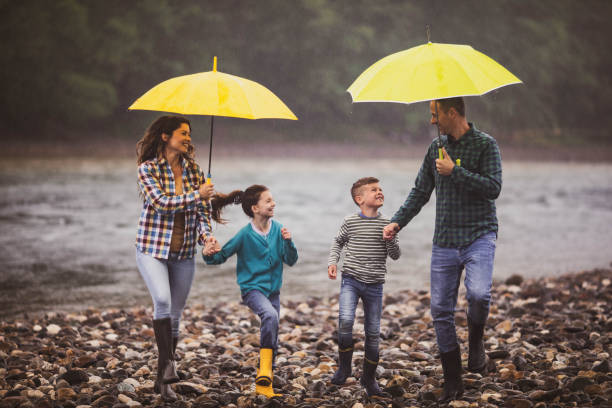 istock Happy family having fun while running on a rainy day at riverbank. 1409439329