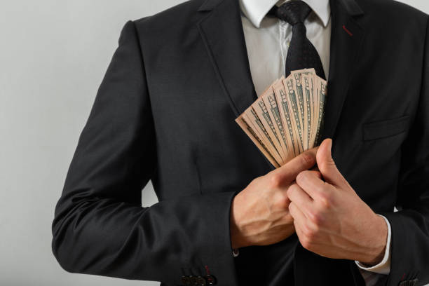 Businessman putting us money into his suit pocket Businessman putting us money into his suit pocket leather pocket clothing hide stock pictures, royalty-free photos & images