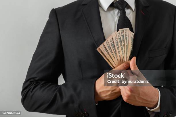 Businessman Putting Us Money Into His Suit Pocket Stock Photo - Download Image Now - Fraud, Dishonesty, Government