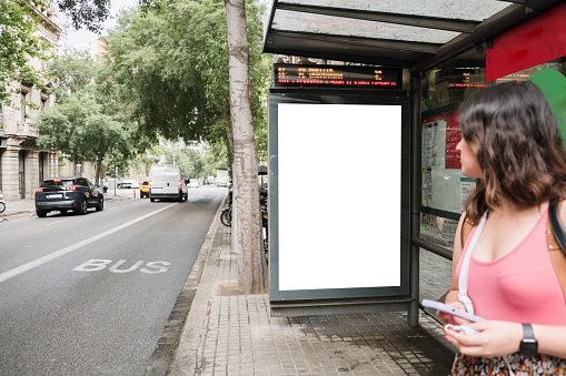 A bus stop in a city street with a blank placard for advertisements