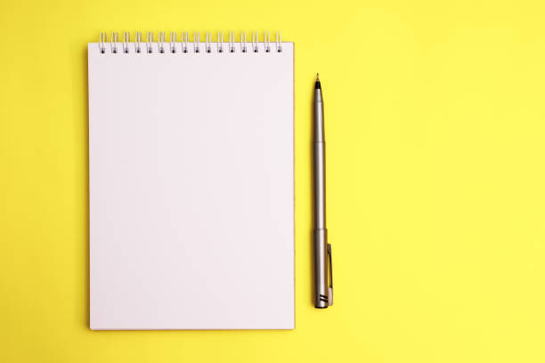 istock Top view on sketchbook and pen on yellow background 1409442626