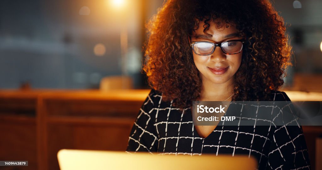 Black business woman using laptop, working late in modern office with copyspace. Smiling African American female working overtime, searching for new project. Lawyer using internet research or study Search Engine Stock Photo