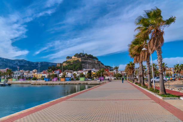 Denia Spain town and palm trees from marina with colourful houses and mountain stock photo