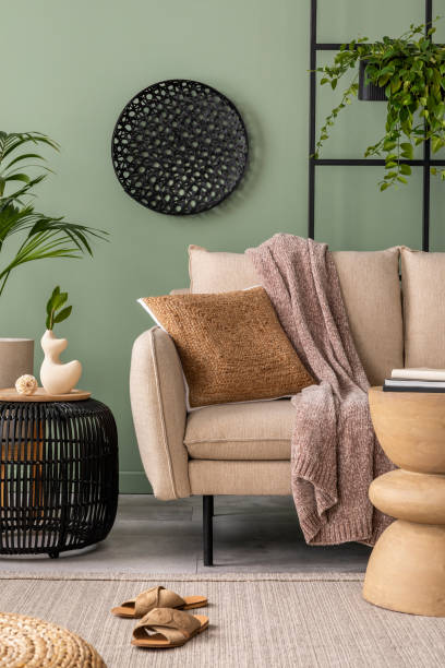 istock Interior design of harmonized living room interior with design beige sofa, coffee table, plants and elegant personal accessories. Brown pillow and plaid. Cozy apartment. Home decor. 1409447138