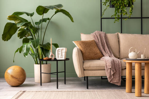 istock Modern composition at living room interior with design beige sofa, coffee table, plants and elegant personal accessories. Brown pillow and plaid. Cozy apartment. Home decor. 1409447140