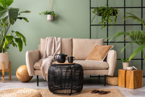 istock Creative composition at living room interior with design beige sofa, black coffee table, plants and elegant personal accessories. Brown pillow and plaid. Cozy apartment. Home decor. 1409447147