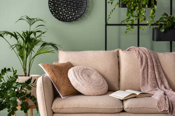 istock The modern composition at living room interior with design beige sofa, coffee table, plants and elegant personal accessories. Brown pillow and plaid. Cozy apartment. Home decor. 1409447218