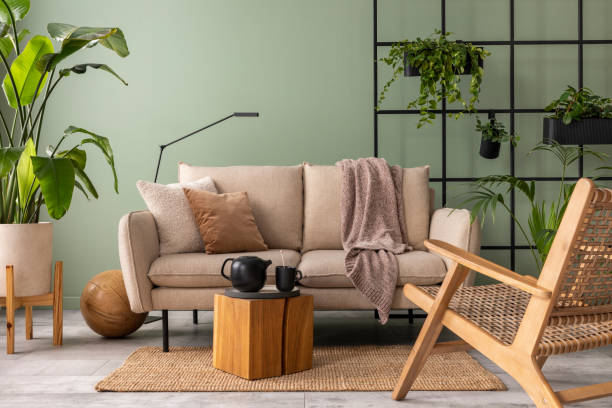 istock The modern composition at living room interior with design beige sofa, wooden coffee table, plants and elegant personal accessories. Brown pillow and plaid. Cozy apartment. Home decor. 1409447220