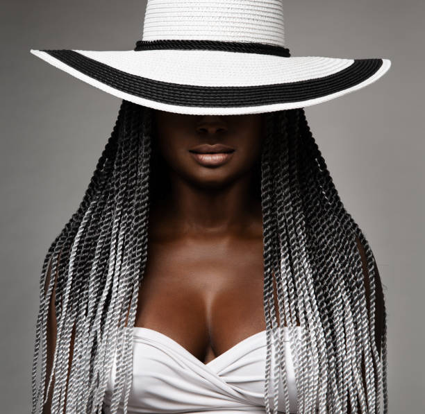 African Woman with Long Braids Hair. Black and White Concept. Beauty Model in Big Hat hidden Face. Afro Hairstyle and Lips Makeup. Sexy Mysterious Women Portrait over Gray Studio Background African Woman with Long Braids Hair. Black and White Concept. Beauty Model in Big Hat hidden Face. Afro Hairstyle and Lips Makeup. Sexy Mysterious Women Portrait over Gray Studio Background black woman hair braids stock pictures, royalty-free photos & images