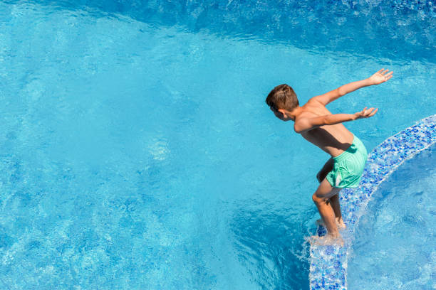 istock Summer active water fun on vacation. Boy child jumping into the pool. 1409448568