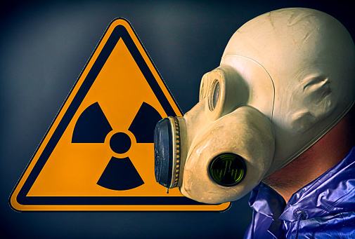 Man in the gas mask near the radiation sign. Chernobyl concept. Dangerous nuclear power.
