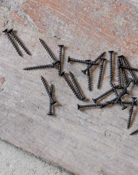 istock Black metal screws lie on the concrete floor. 1409449162