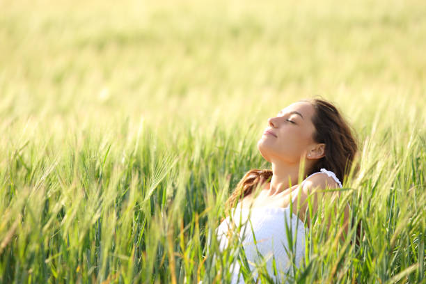 istock Relaxed woman sitting in a field breathing 1409450680