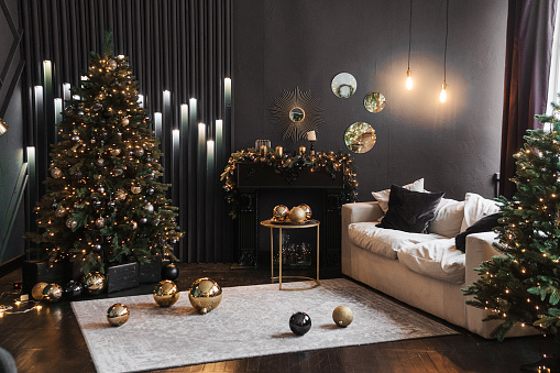 Tver, Russia-November 10, 2021. Christmas interior with a beautiful Christmas tree, sofa, light bulbs and dark background. Home New Year's interior.