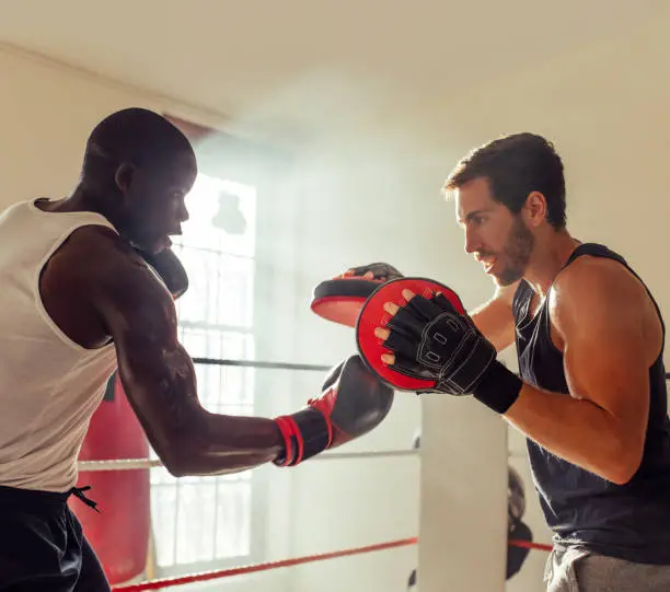 Photo of Boxer practicing uppercut punches with a personal trainer
