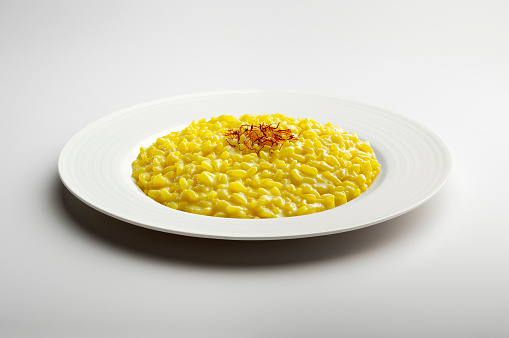 White flat plate with yellow risotto and saffron pistils isolated on white backgroundWhite bowl with yellow saffron risotto isolated on white background