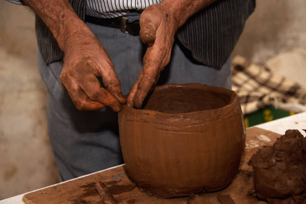 istock Artisan hands shaping moulding clay pot with raw clay material 1409455065