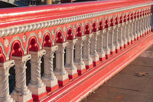 the white and red painted railing of the Blackfriars Bridge in London in evening sunlight