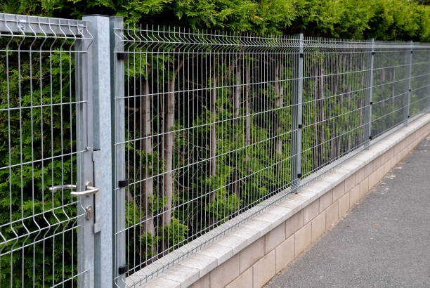istock simple fencing with concrete lining and welded galvanized mesh. in the background behind the goal is a hedge of evergreen conifers. on the street 1409455525