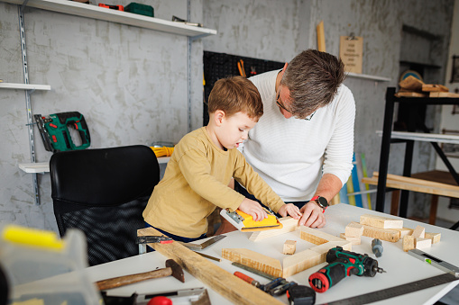 Father and son sanding wooden frame in carpentry workshop