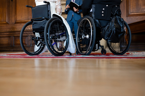 An unrecognisable bride and groom, who are wheelchair users, getting married by an unrecognisable registrar in a wedding venue in Morpeth, North East England.