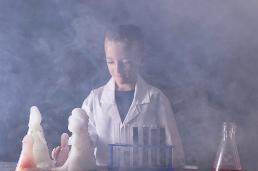 Seven year old wearing a white lab coat conducting a disastrous chemistry experiment.